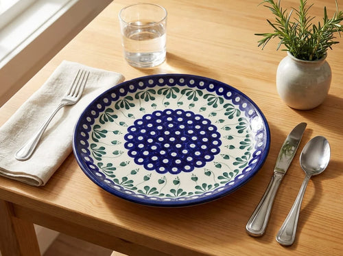 Polish pottery plate in Alyce pattern with silverware and a potted plant on a wood table.