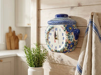 Garden of blue polish pottery cookie jar shaped clock on a wood accent wall