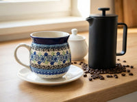 Polish pottery Eliza bubble mug resting on a saucer next to a modern coffee pot and coffee beans