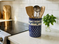 Polish pottery Sweet Annie Utensil jar sitting next to oven and filled with kitchen utensils