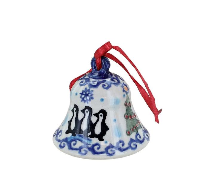 A hand-painted ceramic Christmas bell ornament with three black penguins, blue wave patterns, a small decorated Christmas tree, and a red hanging ribbon, shown on a plain white background.