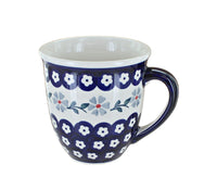 A ceramic mug with a white interior and base, decorated with navy blue scalloped borders and a central floral pattern in white, light blue, and small red accents, shown on a plain white background.