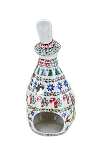 A ceramic Christmas candle holder with a white base decorated with colorful hand-painted holiday motifs including pine trees, snowflakes, candy canes, and reindeer, featuring a cutout front and a small top opening.