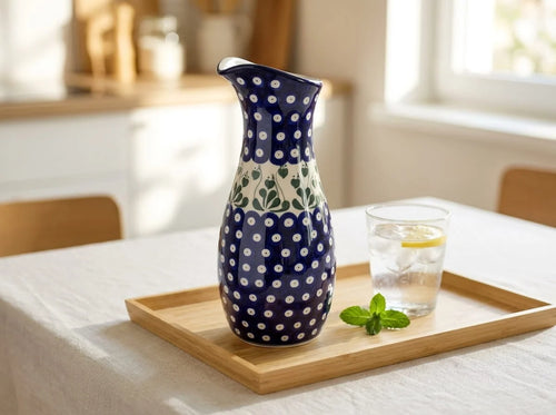 Polish pottery water carafe in Alyce pattern on a wooden tray with fresh min, a glass of water, and a light and breezy kitchen