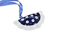 A crescent-shaped glass ornament featuring a dark blue center with white circular evil eye patterns and a white ruffled edge, suspended from a blue ribbon on a white background.