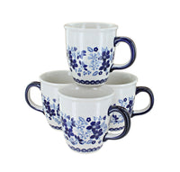 Four white ceramic mugs with dark blue floral patterns and dark blue handles, arranged together on a white background.