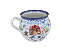 A ceramic mug decorated with a winter holiday scene featuring a gingerbread house, candy canes, snowflakes, and a sleigh on a white background.