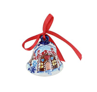 A hand-painted ceramic Christmas bell ornament featuring a gingerbread house design with red, brown, and blue details, topped with a red ribbon bow, shown on a plain white background.