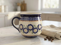Polish pottery Peach Blossom bubble mug on marble countertop next to a sprinkle of coffee beans and a linen napkin