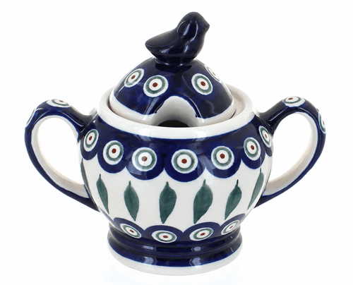 A ceramic sugar bowl with a matching lid featuring a bird topper, decorated with a traditional Polish pattern of blue, white, green, and red concentric circles and leaf motifs.