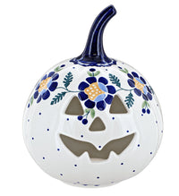 A white ceramic decorative pumpkin with a carved jack-o'-lantern face, decorated with blue flowers, green leaves, and blue dots, featuring a dark blue stem.