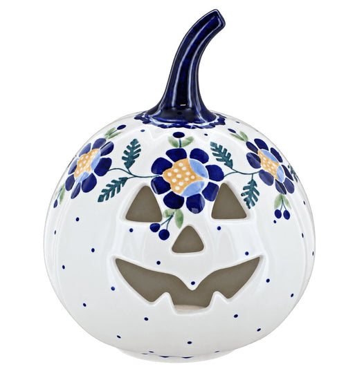A white ceramic decorative pumpkin with a carved jack-o'-lantern face, decorated with blue flowers, green leaves, and blue dots, featuring a dark blue stem.
