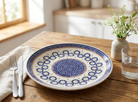 Polish pottery plate on rustic kitchen table with silverware and a vase of flowers