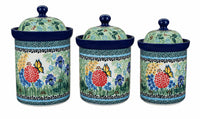 Three ceramic canisters with matching lids, decorated with a colorful floral and butterfly pattern on a white background.