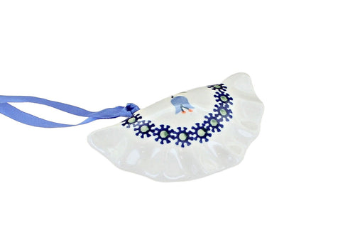 A white ceramic Christmas ornament shaped like a clam, decorated with a blue floral border and a small blue bird, complete with a blue hanging ribbon, shown on a plain white background.
