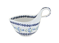 A white ceramic saucepan with a blue floral pattern and a loop handle, shown on a plain white background.