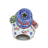 A ceramic snowman figurine decorated with a blue and white speckled hat, a red scarf, and red and blue floral patterns on a white body, isolated on a white background.