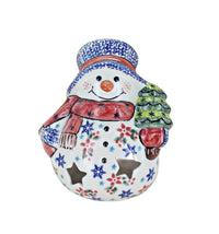 A ceramic snowman figurine decorated with a blue and white patterned hat, a red scarf, a green Christmas tree, and colorful floral details on a white background.