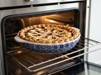 A baked pie in a blue and white patterned ceramic dish sitting on the middle rack of an oven.